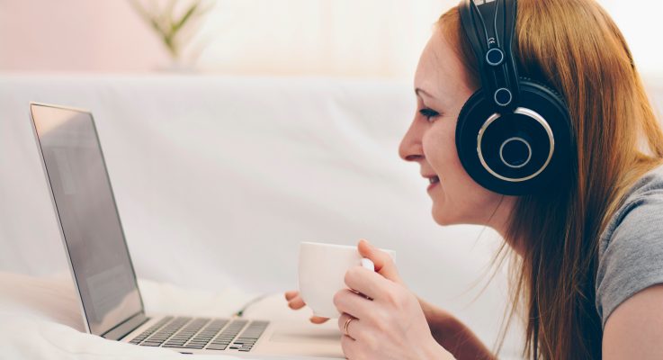 Lady on computer with headphones and tea during social isolation