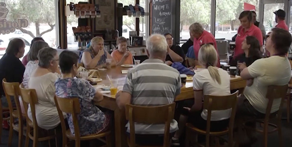 Participants of the connections program sitting around a large table at a cafe