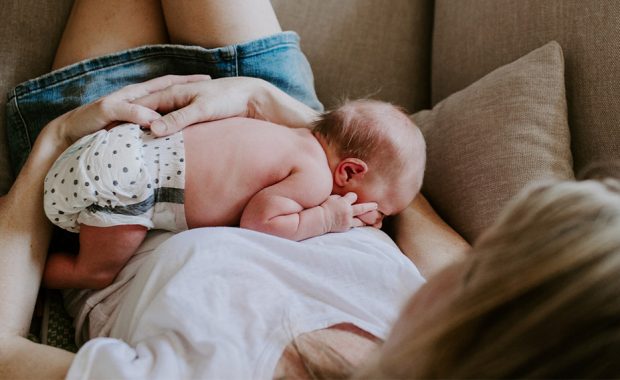 mother sitting on couch holding baby, shot from above